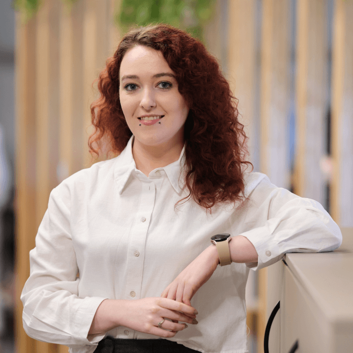 Smiling woman in grey shirt sitting in red conference room at Alkermes