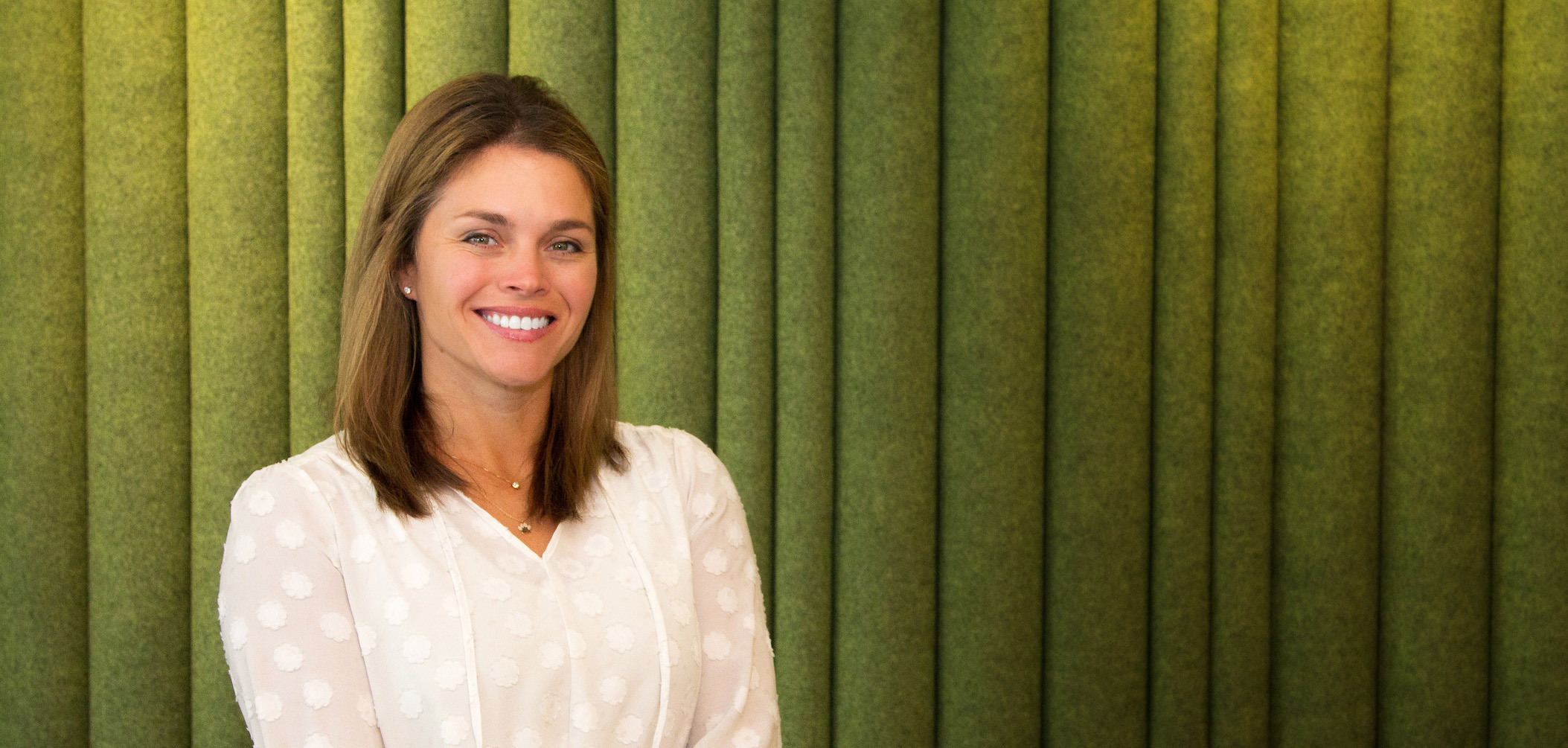 Woman Standing in front of green curtain.
