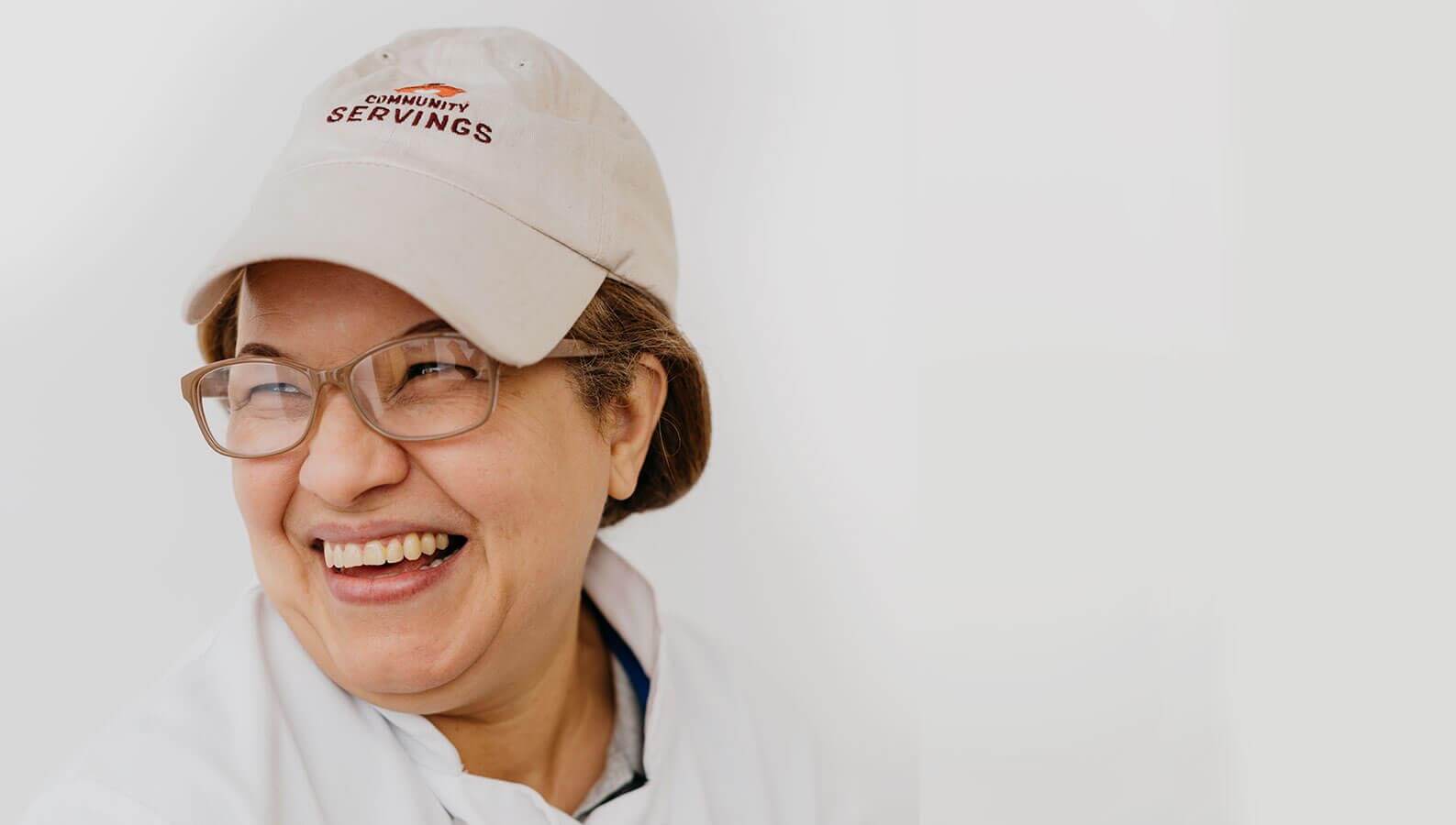 Woman wearing hat laughing against white background
