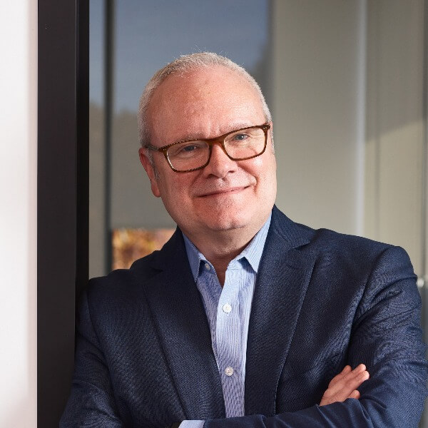 Smiling man with glasses leaning against doorway of conference room at Alkermes