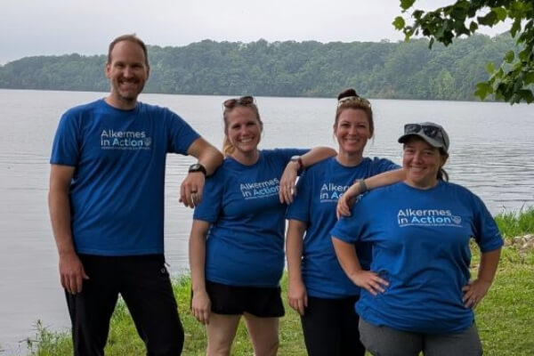group of employees wearing Alkermes in Action t-shirts in front of a lake