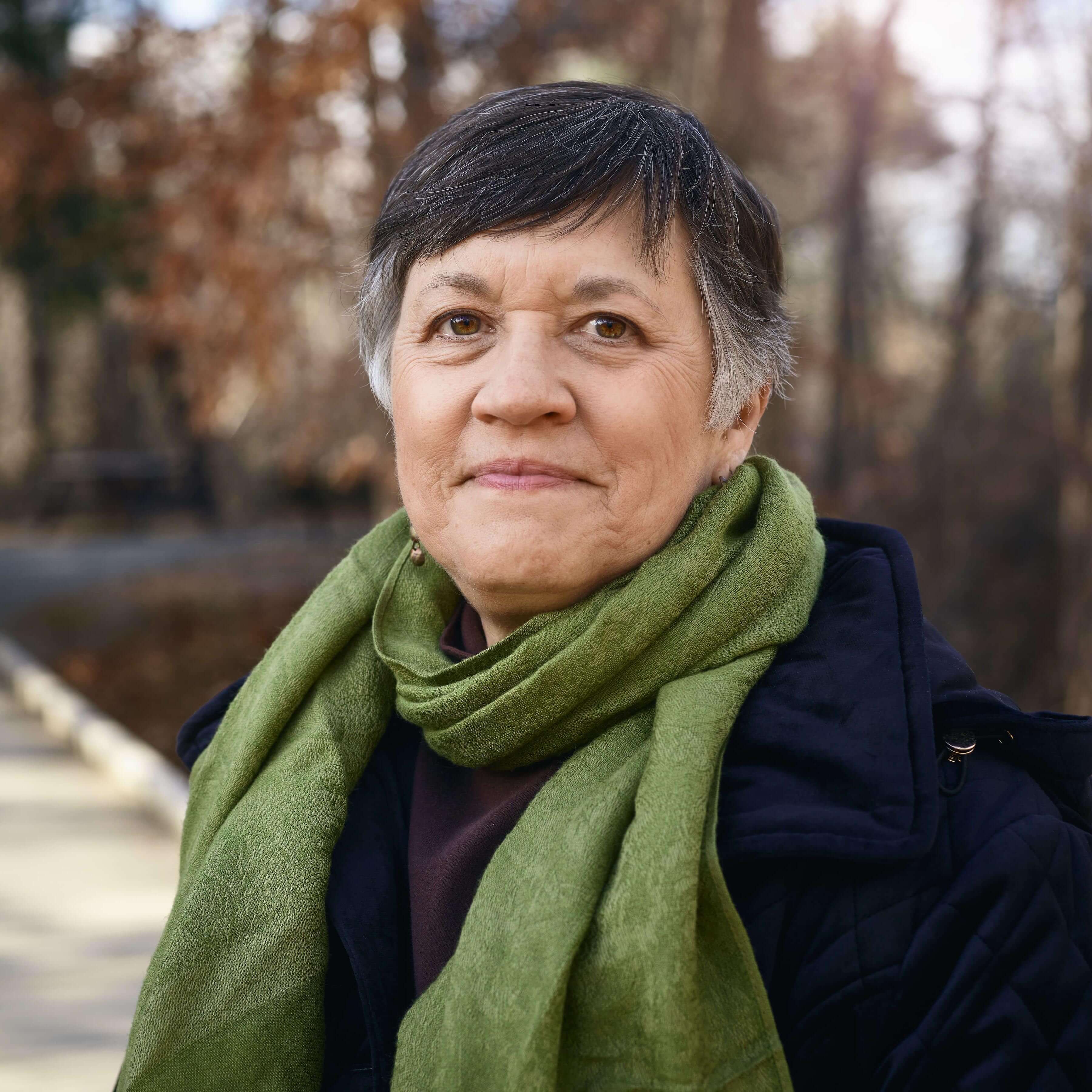 Portrait of woman outdoors with green scarf.
