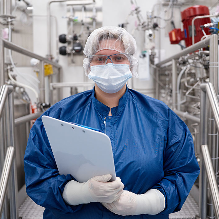 Portrait of employee standing masked in manufacturing lab