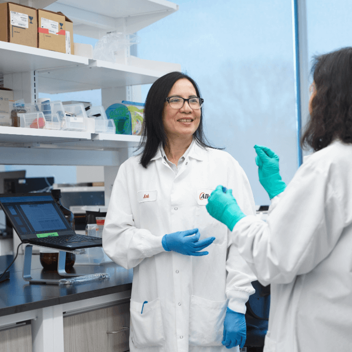 Man standing in lab coat with mask on in laboratory area at Alkermes.